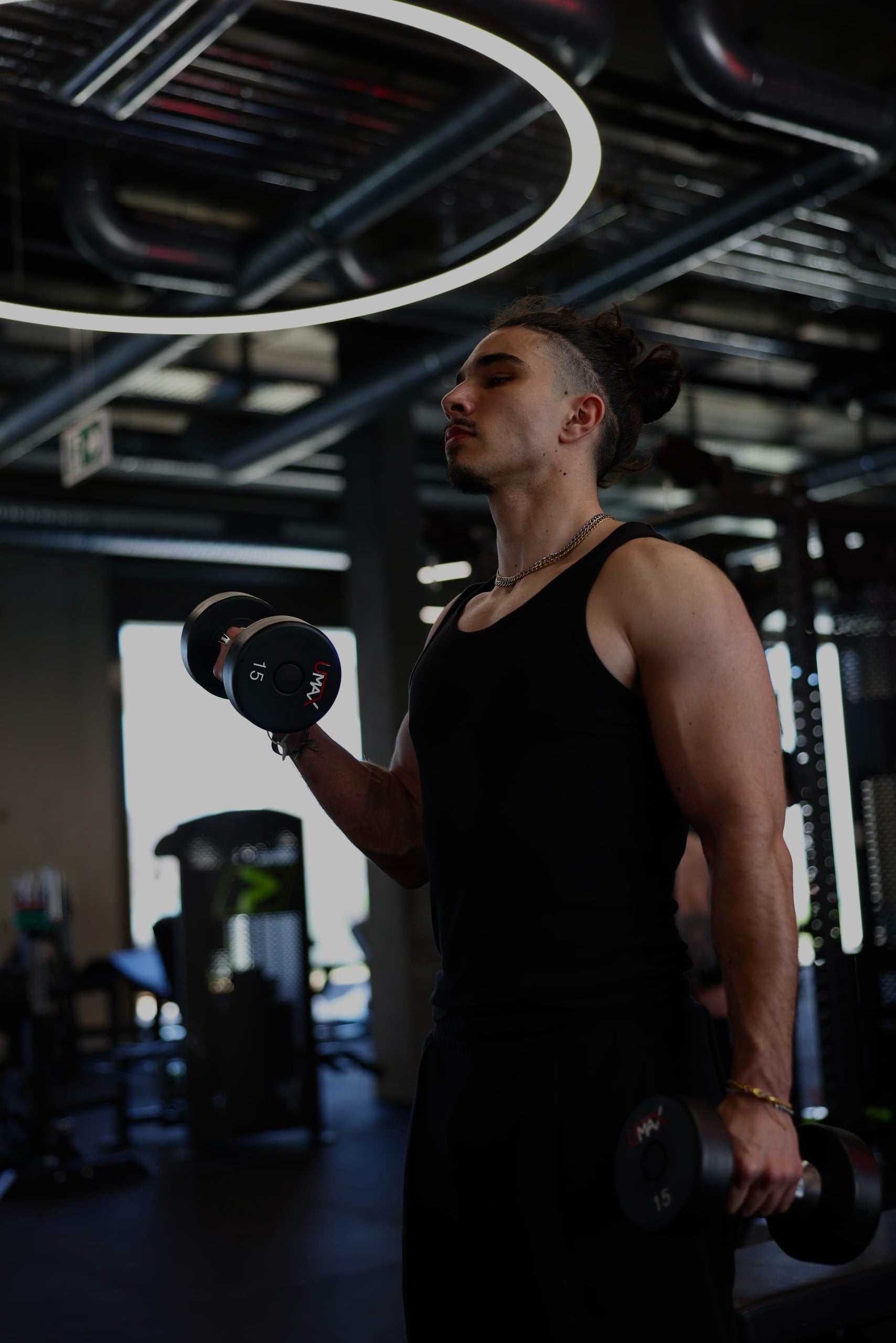 ELEVATE member doing dumbbell curls under the ring lights on the gym floor